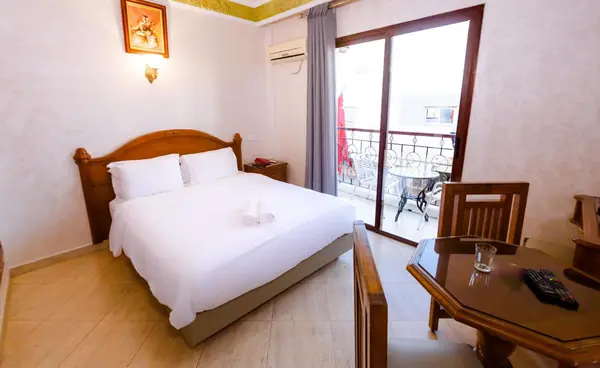 Double room at Hôtel Lynx: a large double bed, a table and chair, and the glass door open onto a wrought-iron balcony.