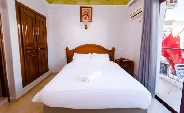 A room at Hôtel Lynx with a large double bed, carved wooden wardrobe and a window onto the street flags.